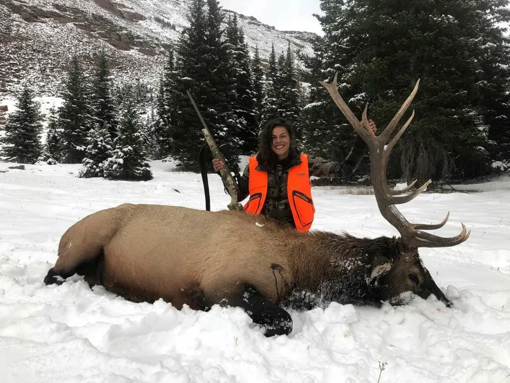 natalie krebs kneeling behind a bull elk