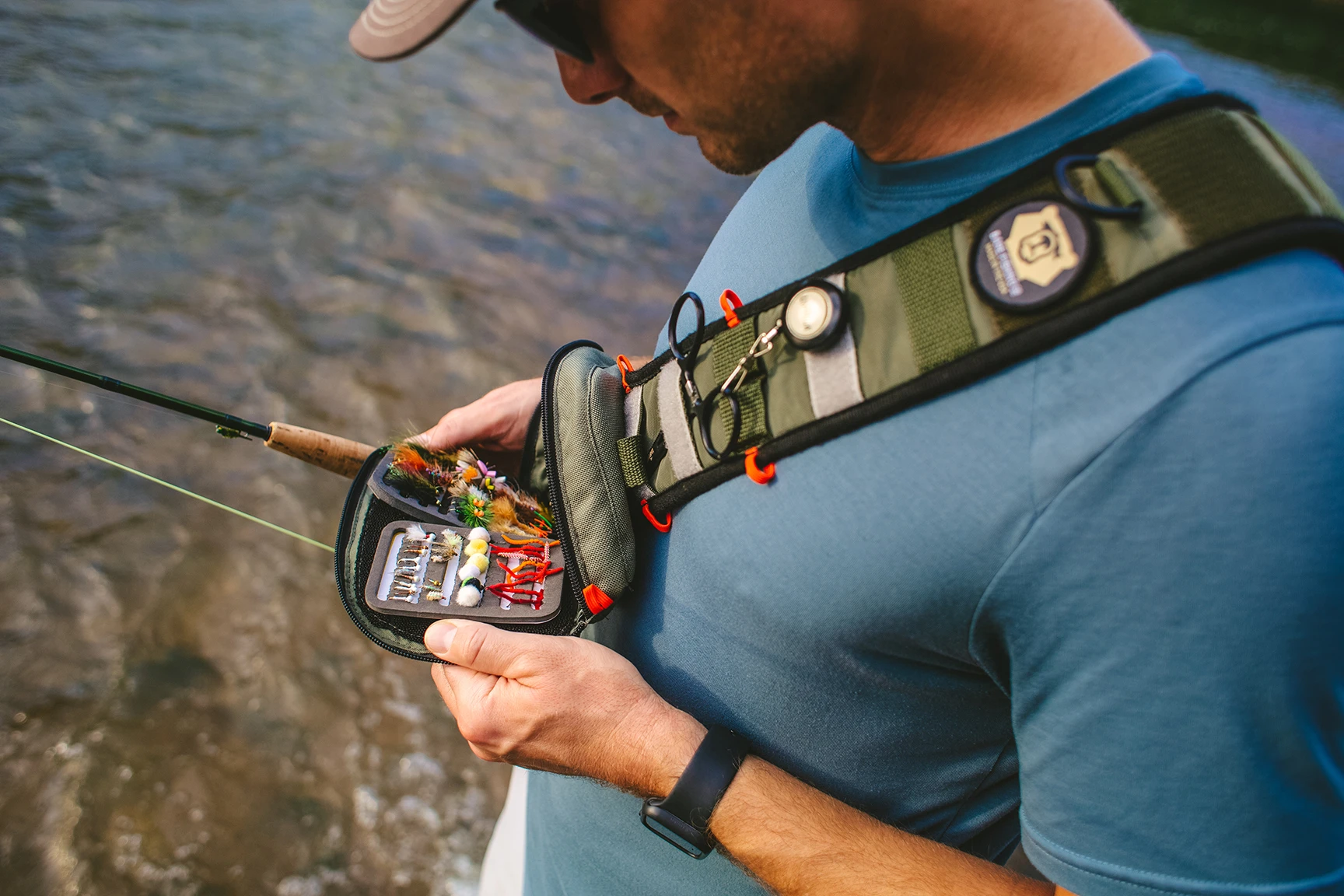 Angler looking into sling pack with a pad of flies