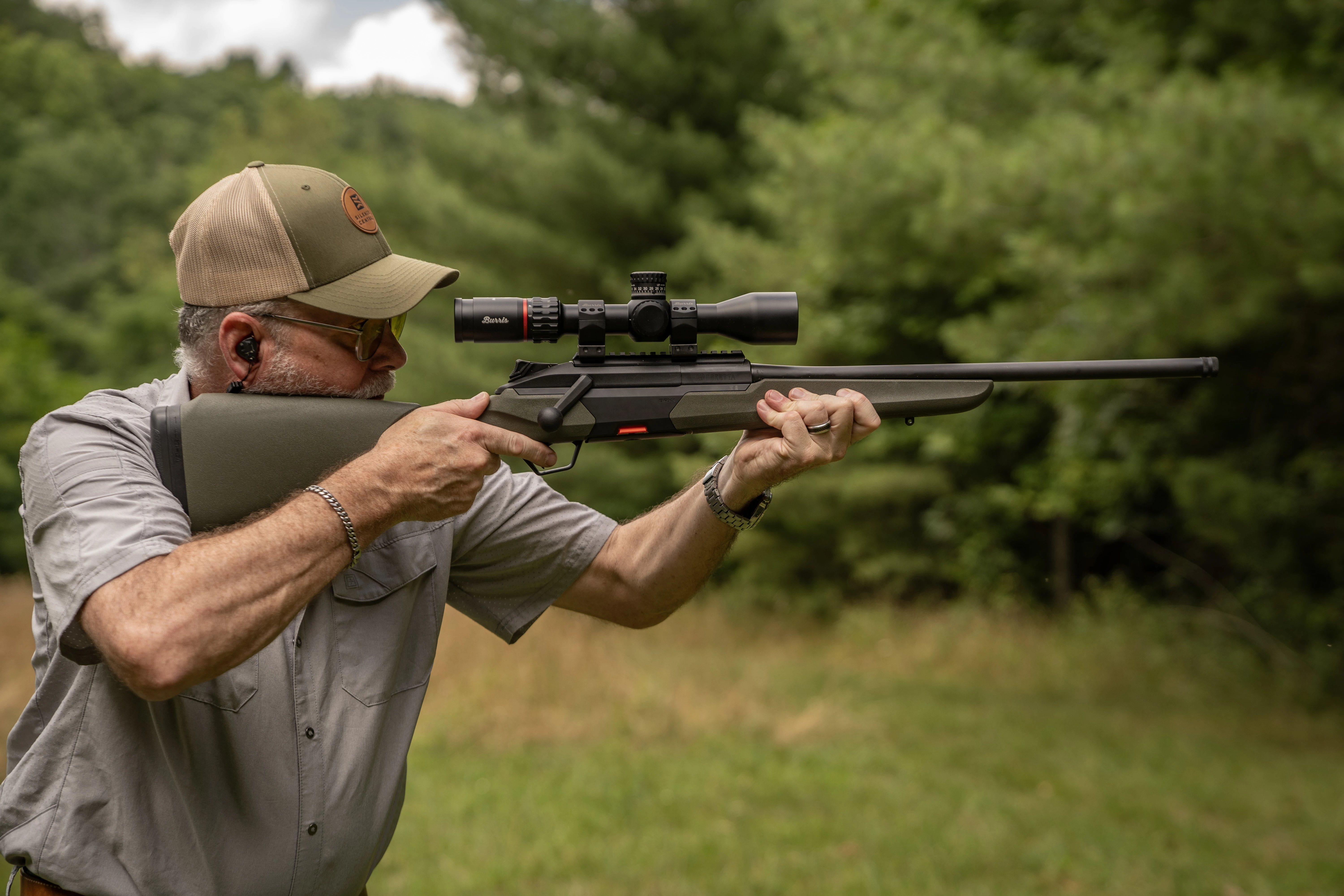 A shooter fires the Baretta BRX1 rifle from the offhand position, with woods in background. 