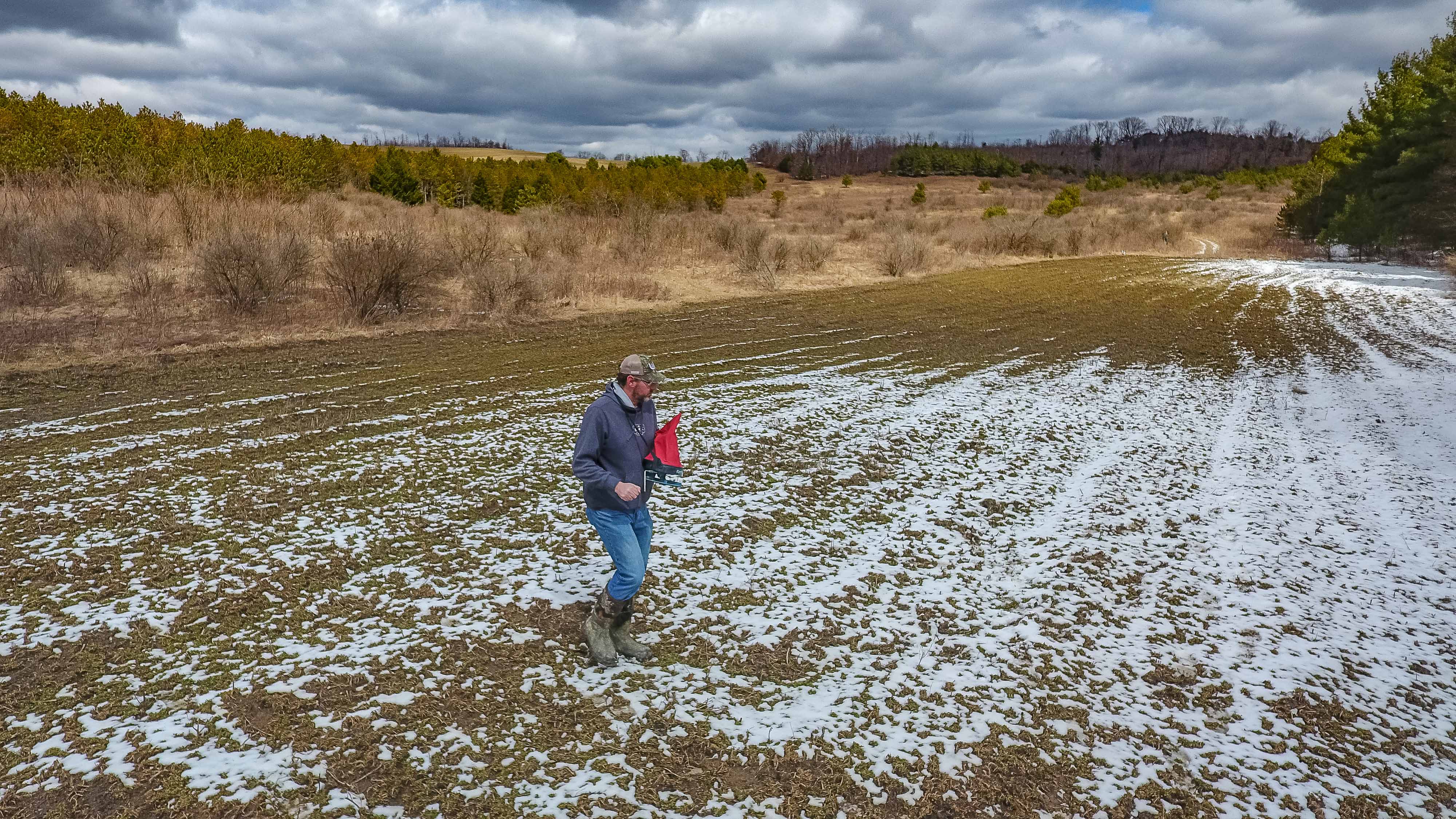 Photo of man spreading seed on a field, showing when to plant food plots for deer.