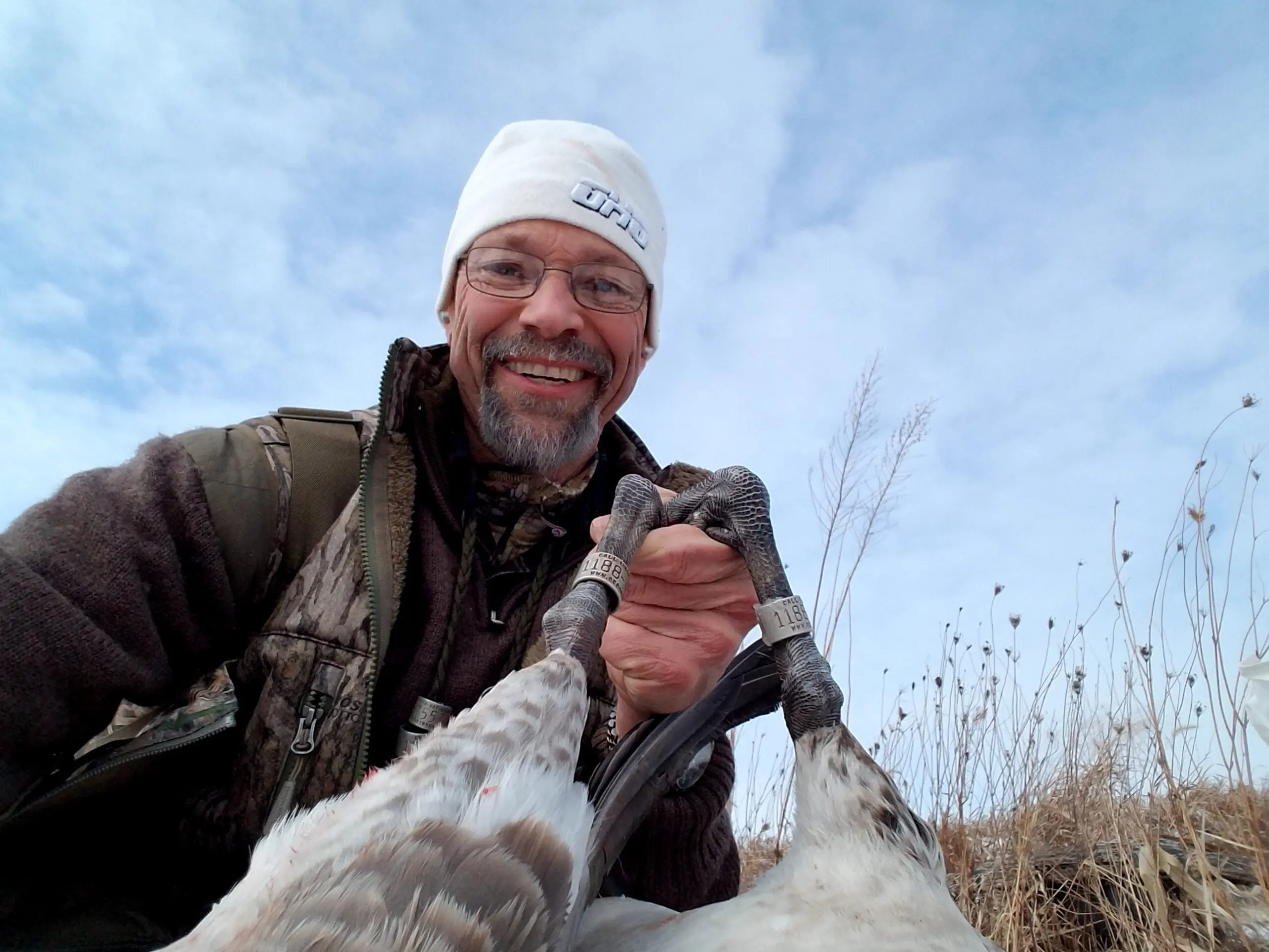 Man showing the legs of a dead goose.