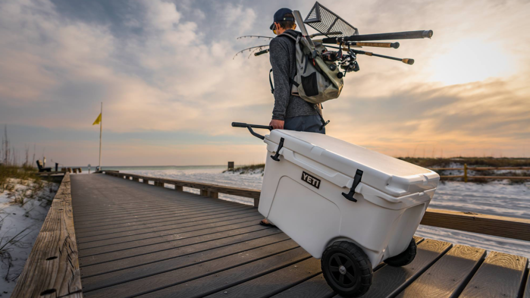 Fisherman wheeling Yeti Tundra Haul cooler down pier