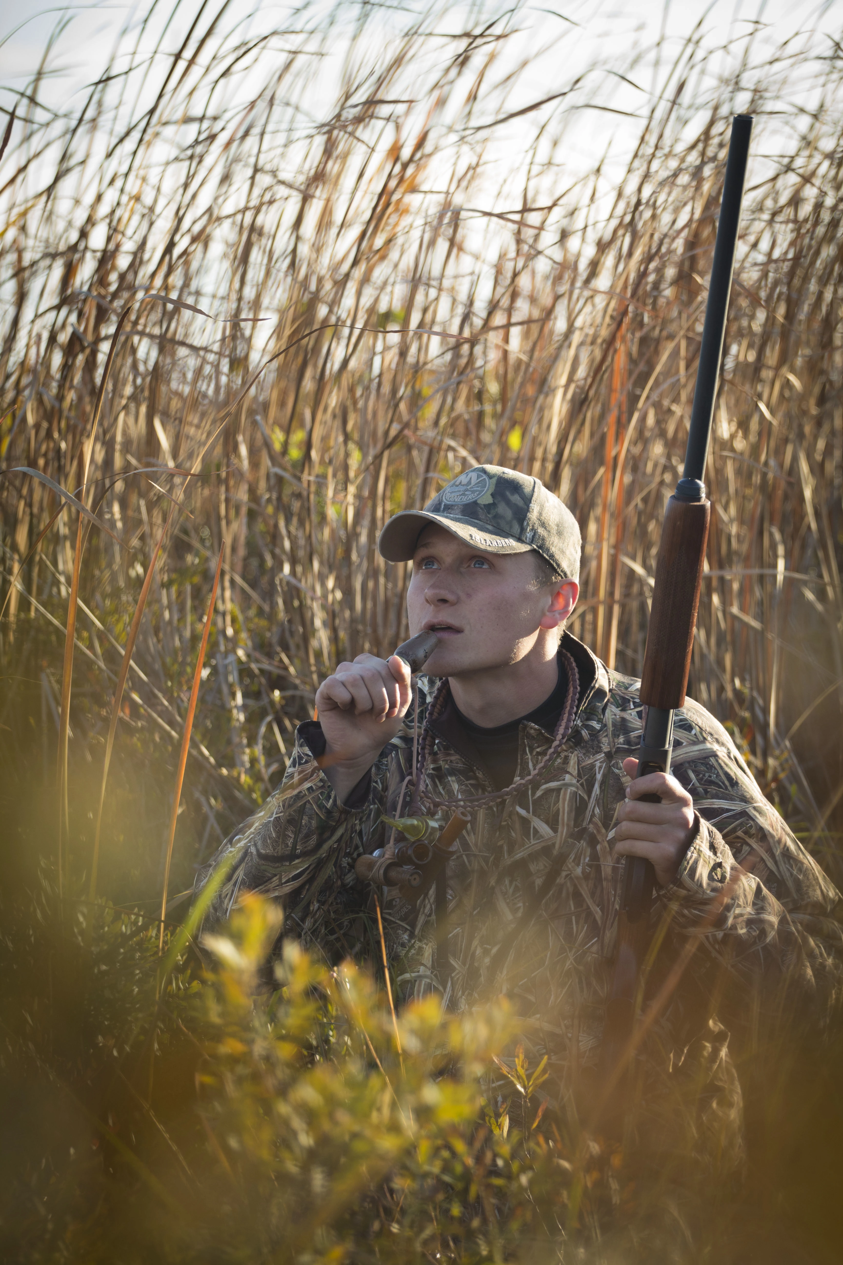 Duck hunter holds a call to his mouth as he looks toward the sky