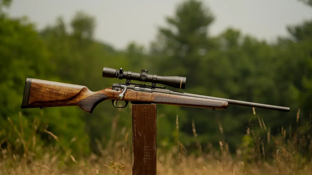 rifle is balanced on post with trees on background