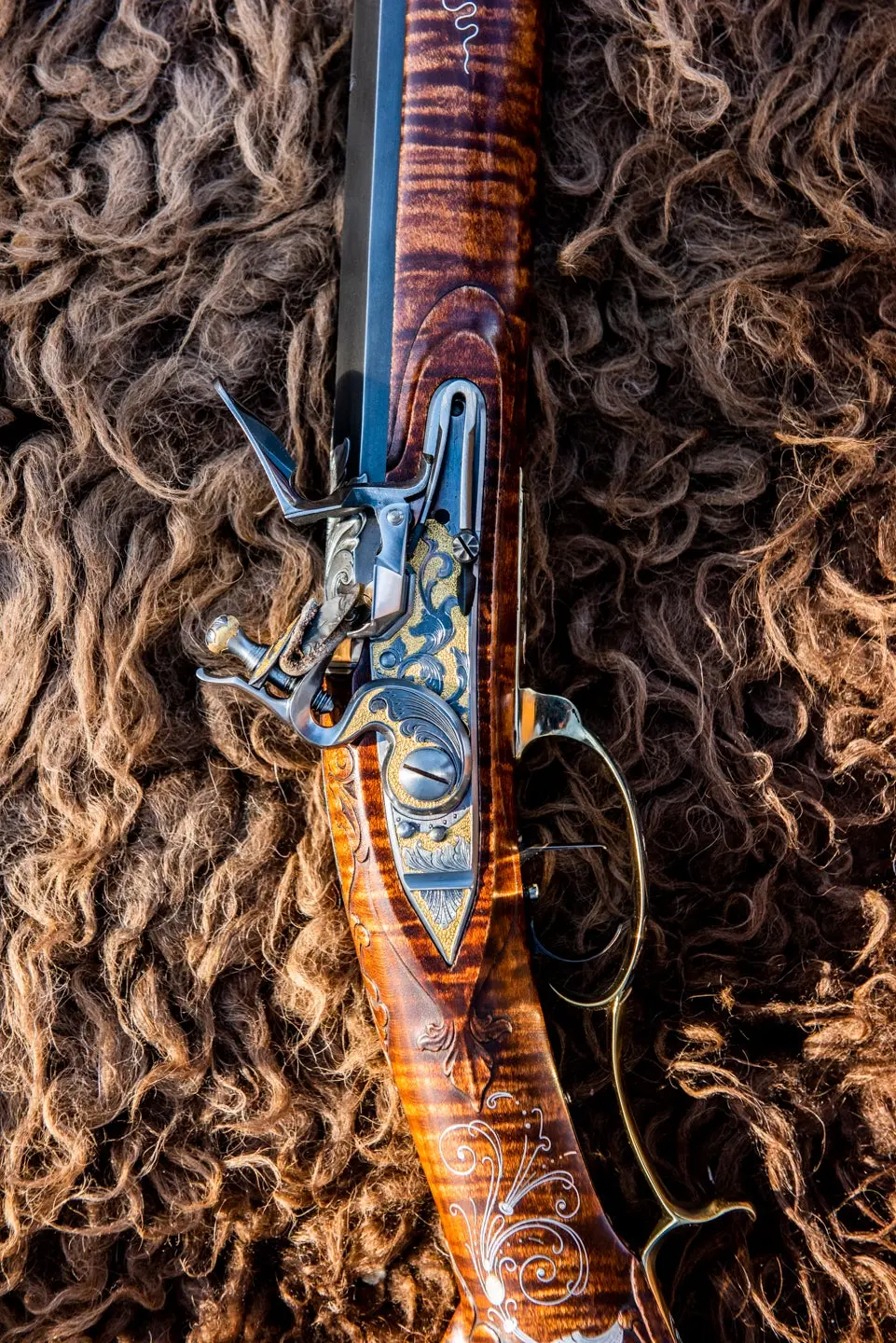 An ornately decorated flintlock rifle lying on a buffalo hide