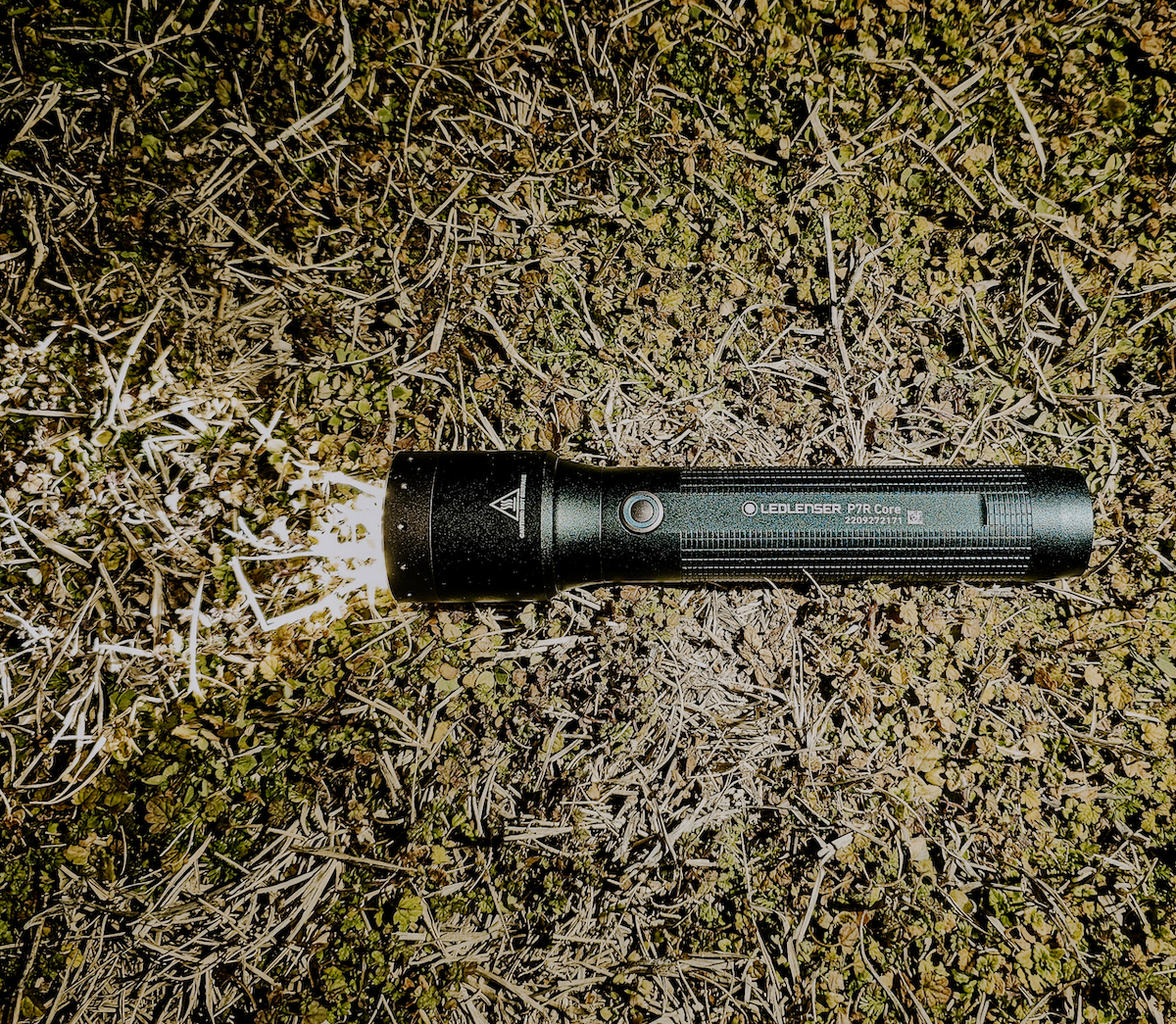 Ledlenser P7R Flashlight turned on laying on grass