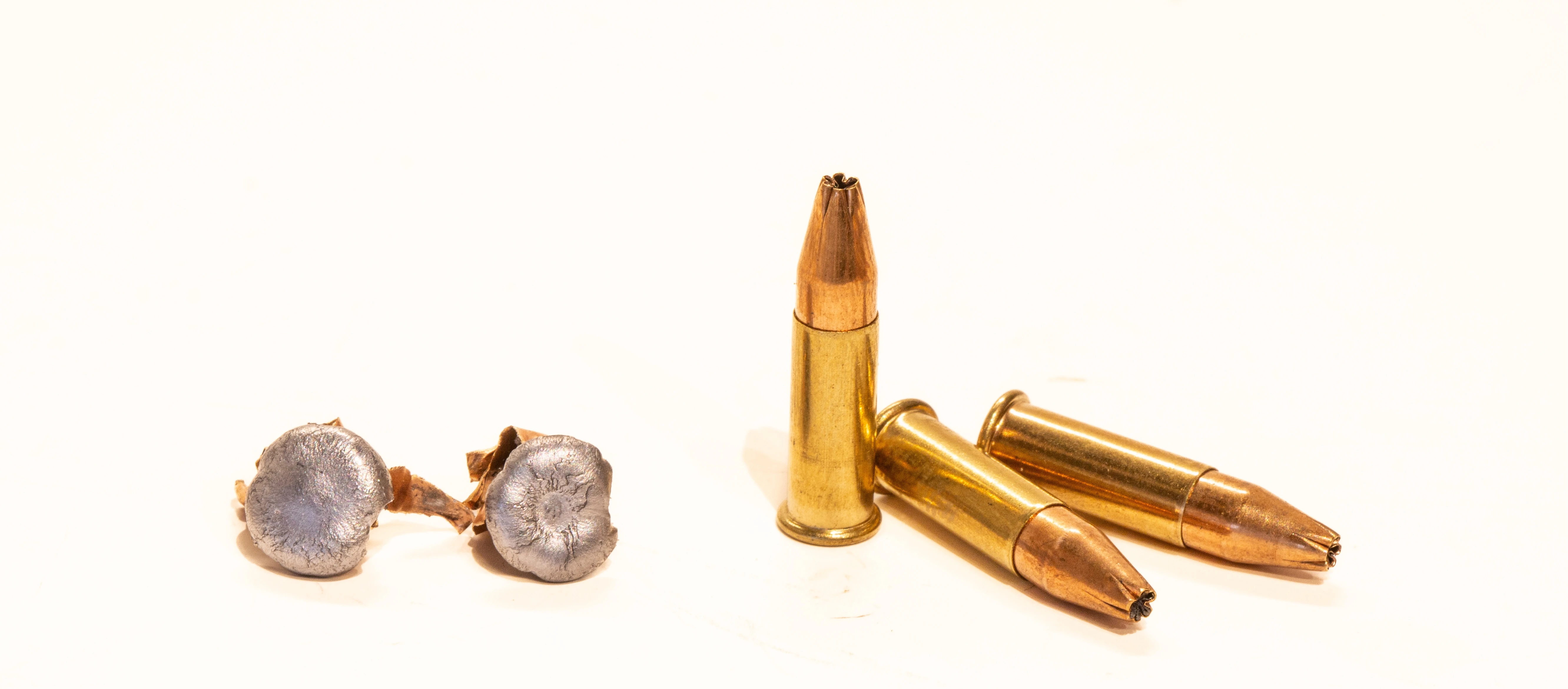 Three unfired 21 Sharp cartridges next to a pair of fired and deformed 21 Sharp hollow-point bullets.