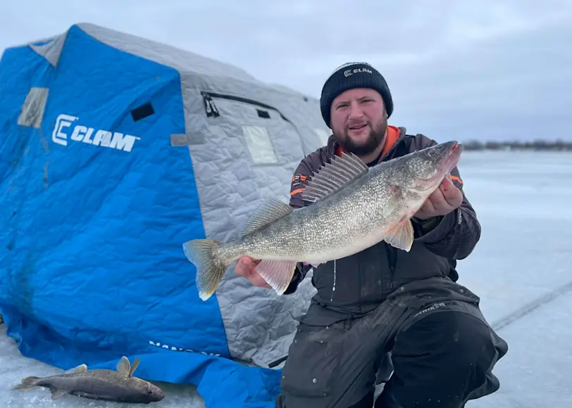 An angler poses with a trophy walleye caught through the ice in Upstate New York. 