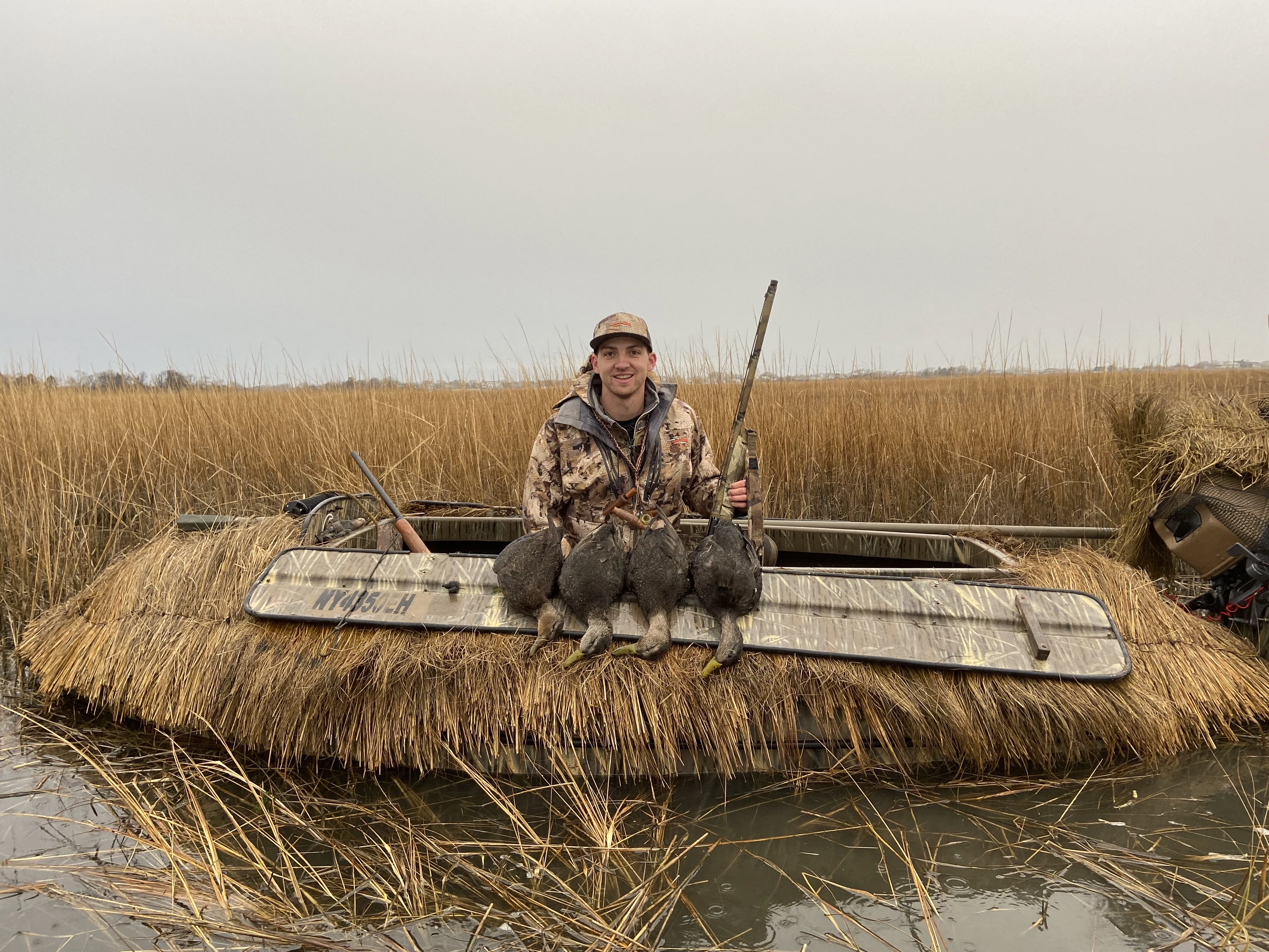 A hunter poses with four black ducks