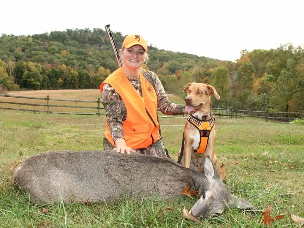 How to name your dog: female hunter kneeling by blood-tracking dog and doe