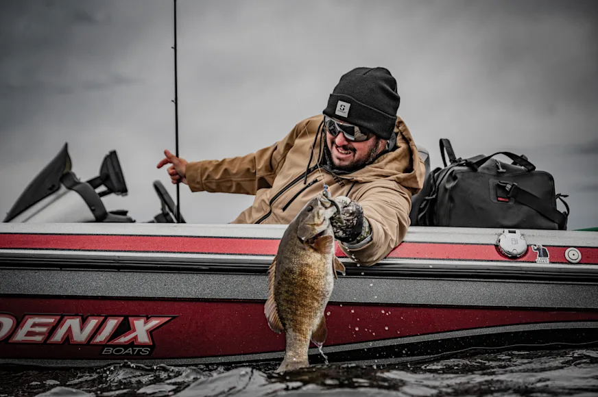 Angler holding bass next to boat