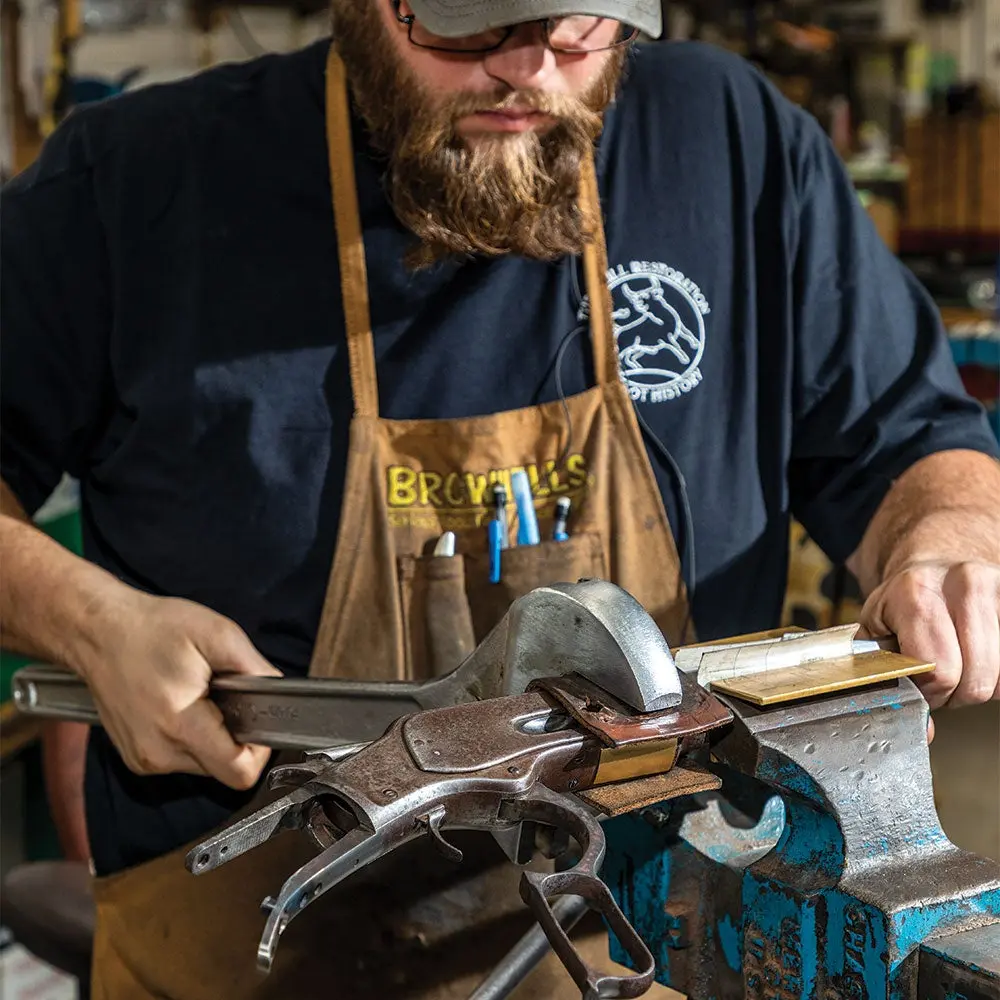 a gunsmith holding a wrench while rebarreling a rifle