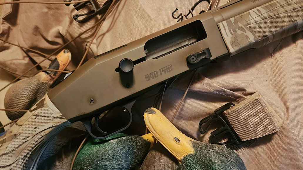 Mossberg 940 Pro Waterfowl shotgun resting on a hunting vest dear mallard duck decoys.