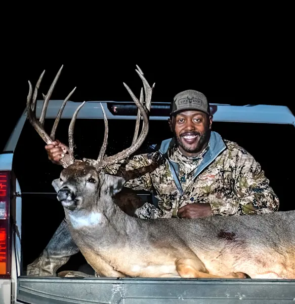 Kansas bowhunter Chris Sykes poses in the back of a pickup truck with a huge whitetail buck he took. 