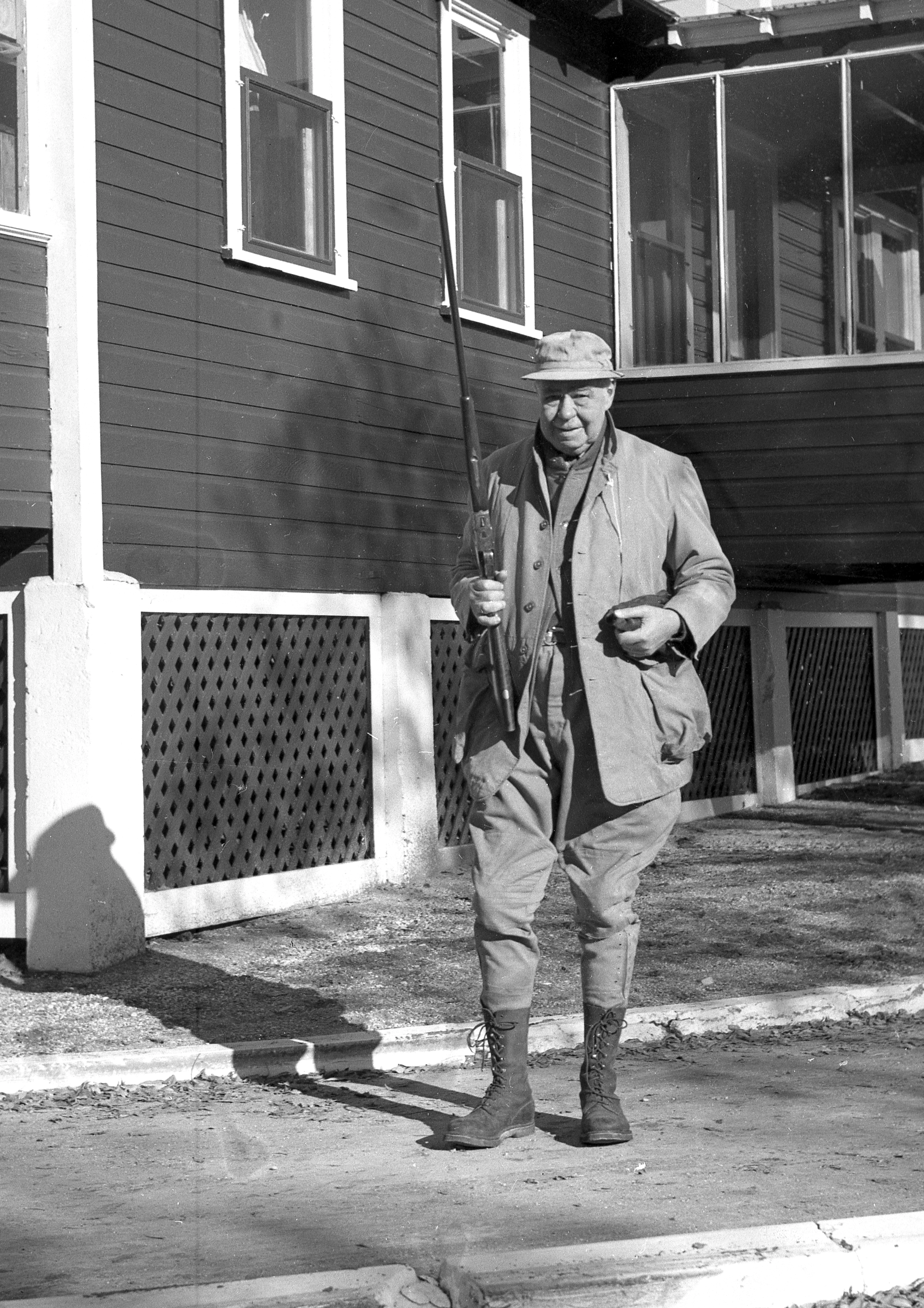 Black and white photo of hunting holding up shotgun