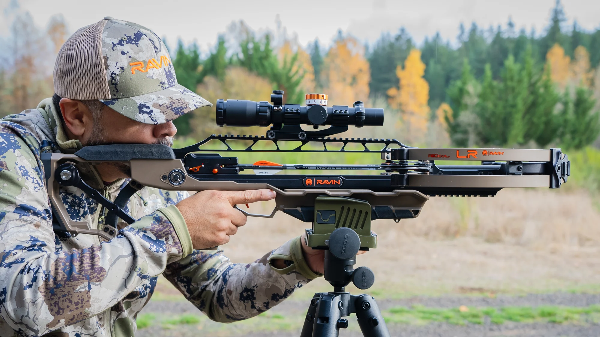 A shooter fires the new Ravin LR crossbow from a tripod at an outdoor range. 