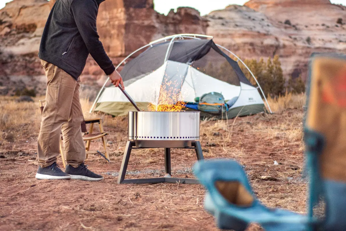 Camper lighting a fire in the Solo Stove Bonfire smokeless fire pit