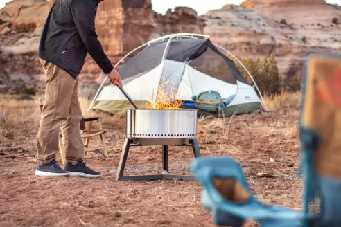 Camper lighting a fire in the Solo Stove Bonfire smokeless fire pit