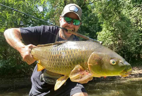 fly fisherman holds a carp