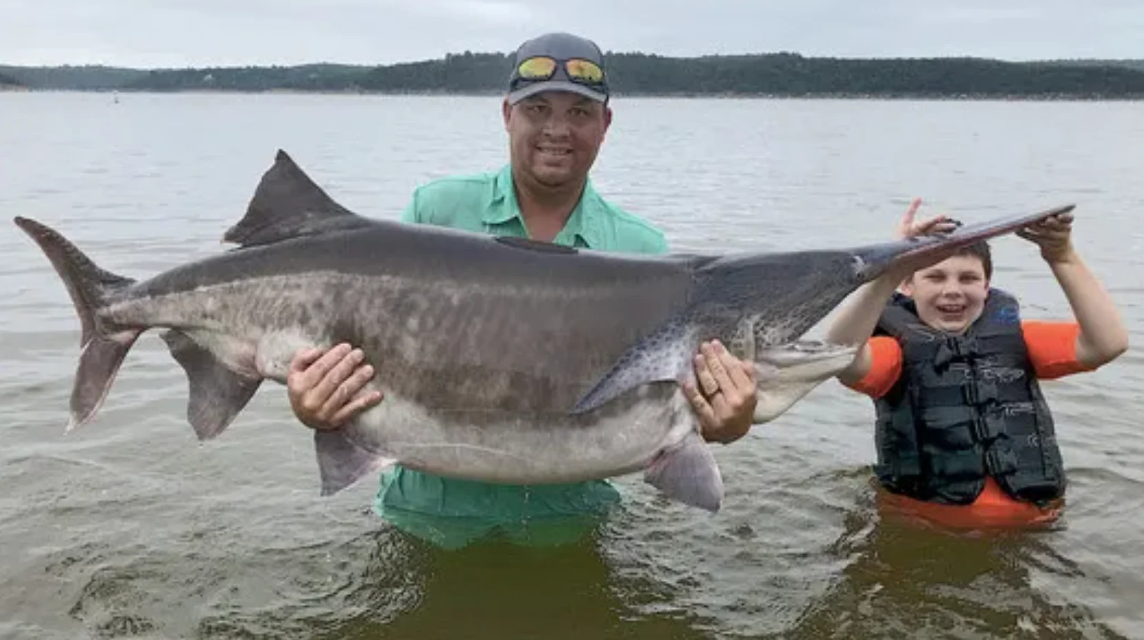 An angler poses with a record-breaking paddlefish caught in Oklahoma.