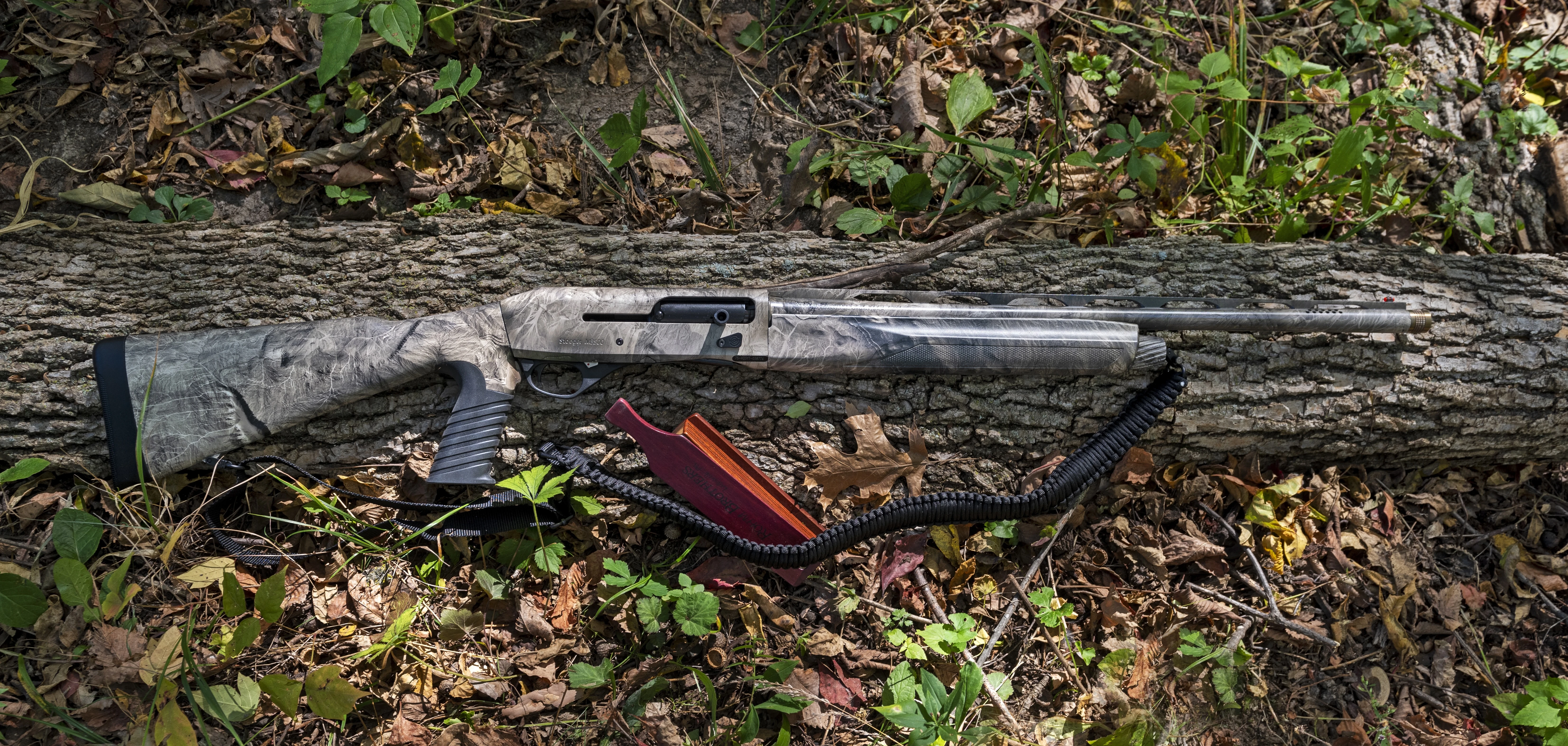 The new Stoeger 3500 Predator/Turkey shotgun lying on a log with a turkey call. 