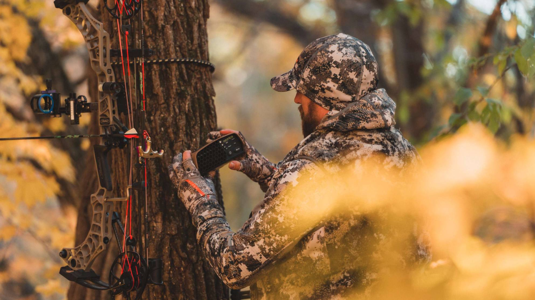 Bowhunter mounting Ozonics Scent Eliminator on tree near stand