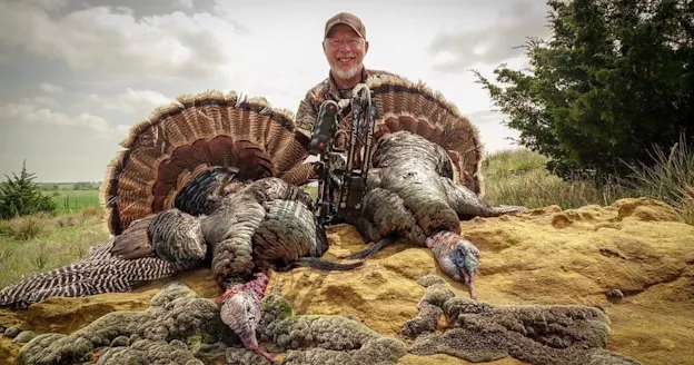 Philip Vanderpool poses with a pair of bow-killed longbeards.