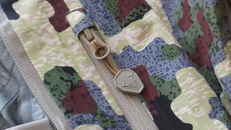 A close up of the Forloh All Clima jacket's zippers on a green, black, and tan camo background. 