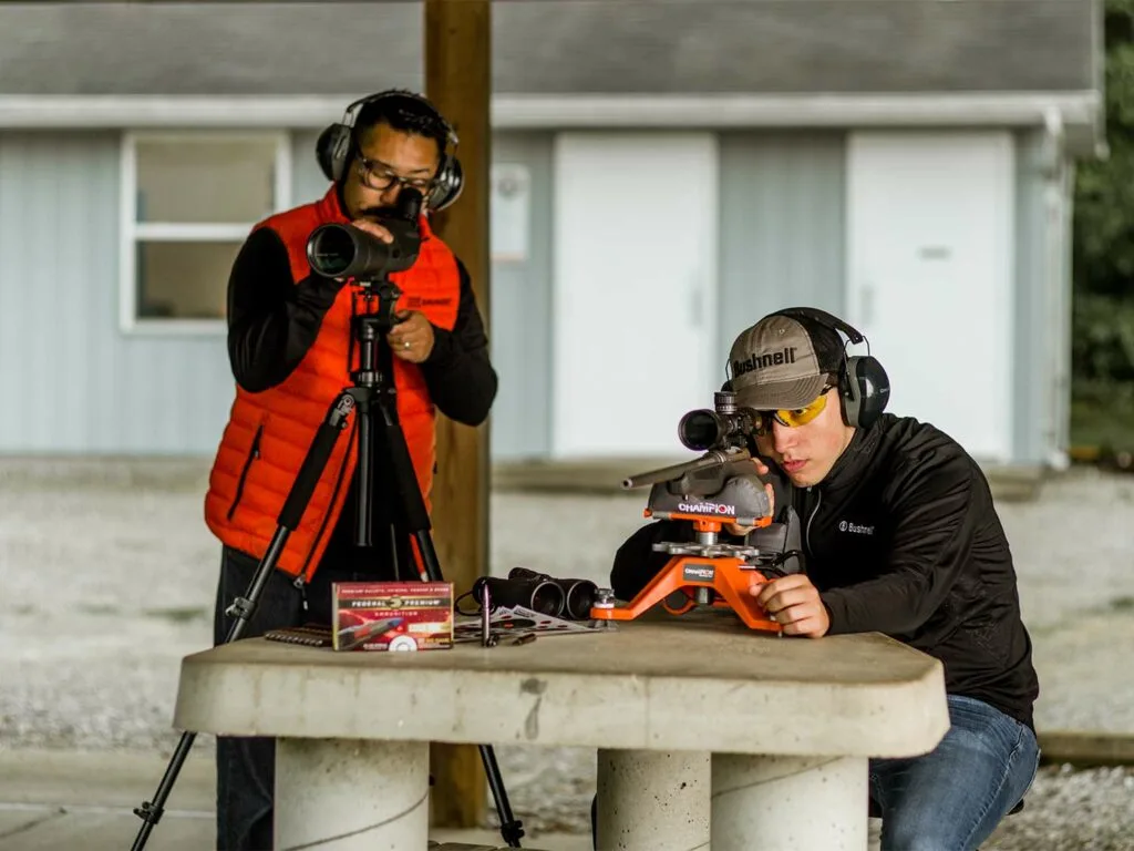 Two men sighting in a rifle at a shooting range. 