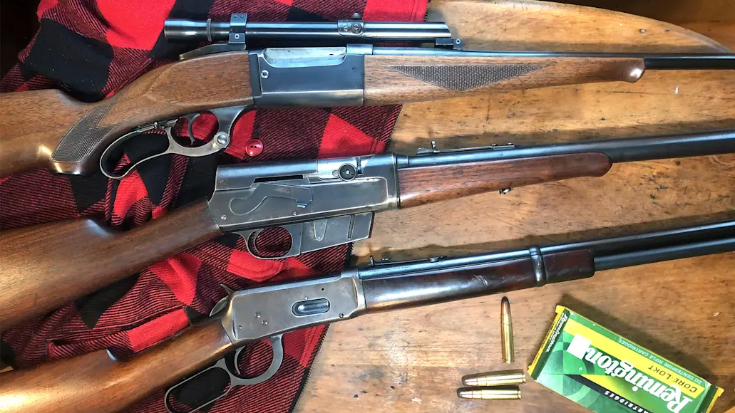 Three classic deer rifles sitting on a table with a box of Remington ammunition. 