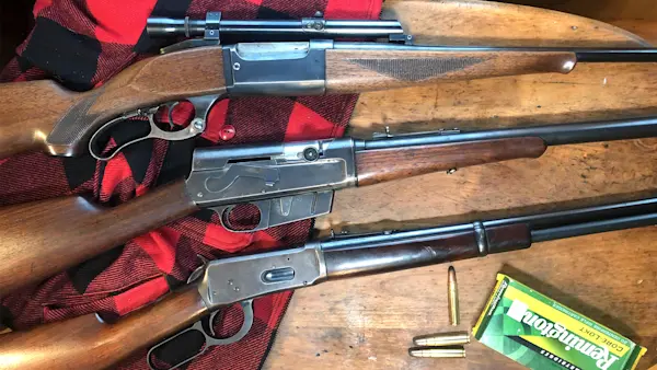 Three classic deer rifles sitting on a table with a box of Remington ammunition. 