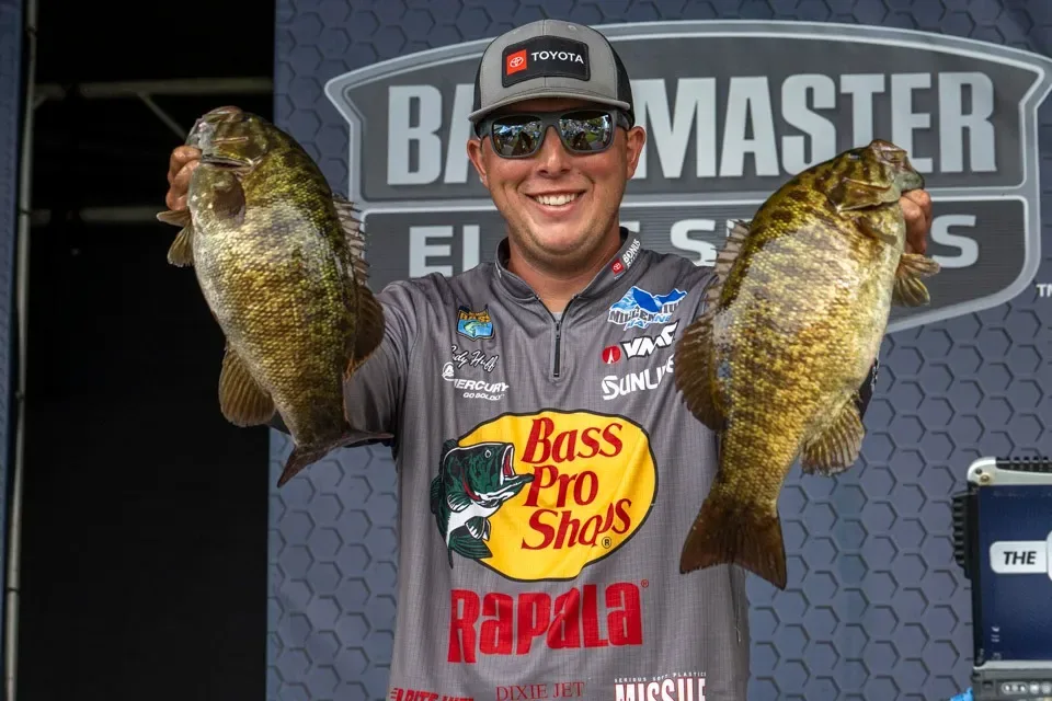 Bassmaster angler Cody Huff hoists a pair a big smallmouth bass at a tournament.