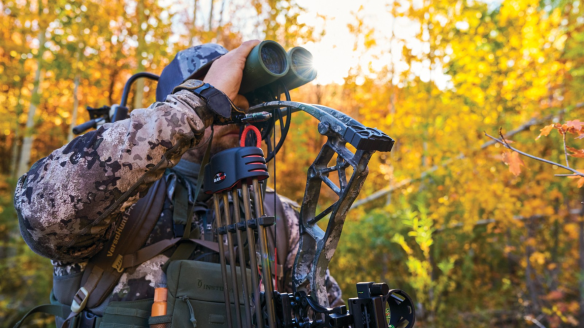 Bowhunter wearing Cabela's gear looking through binoculars