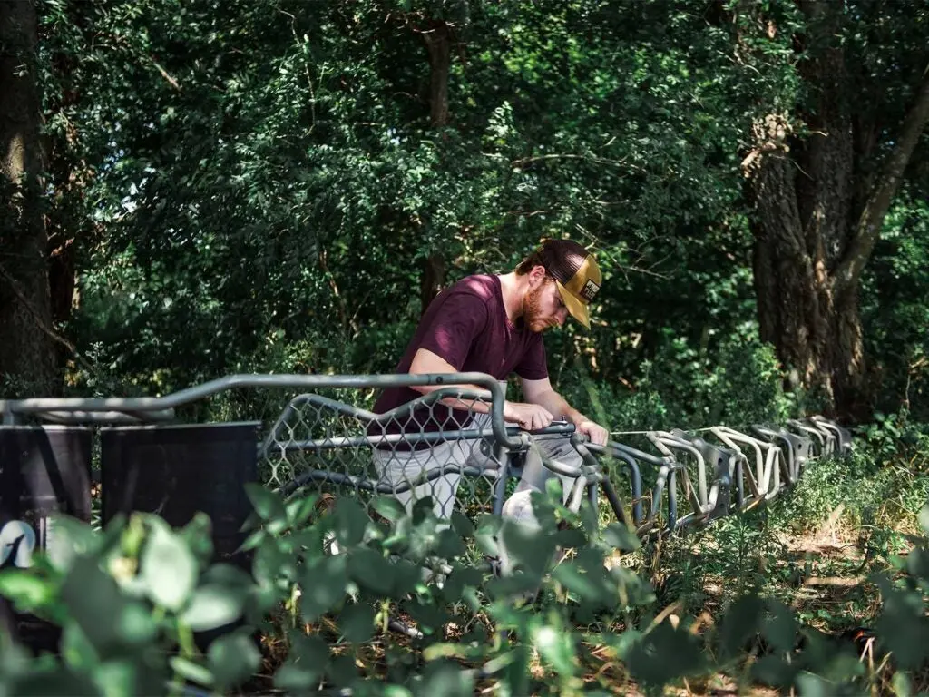 A hunter works to assemble a ladder attached to a tree stand.