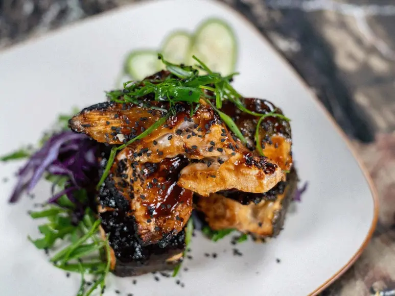 Marinated and grilled trout collars on a bed of greens.