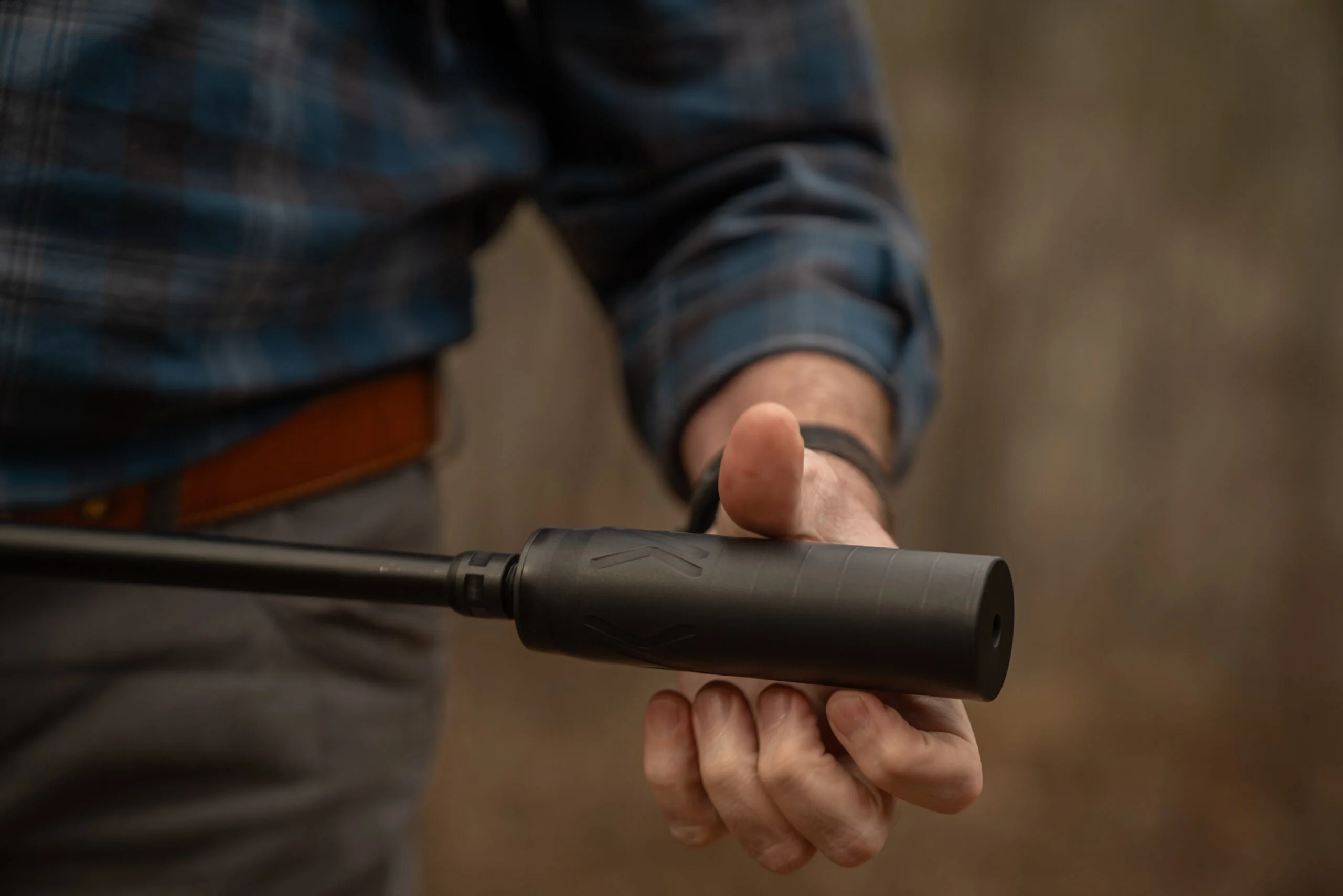 A shooter threads a suppressor onto the barrel of a Colt CBX TAC Hunter rifle.