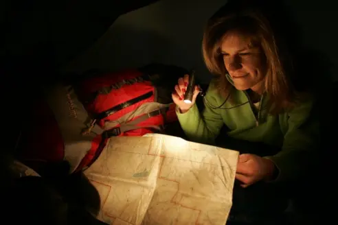 Woman shining a flashlight on a map