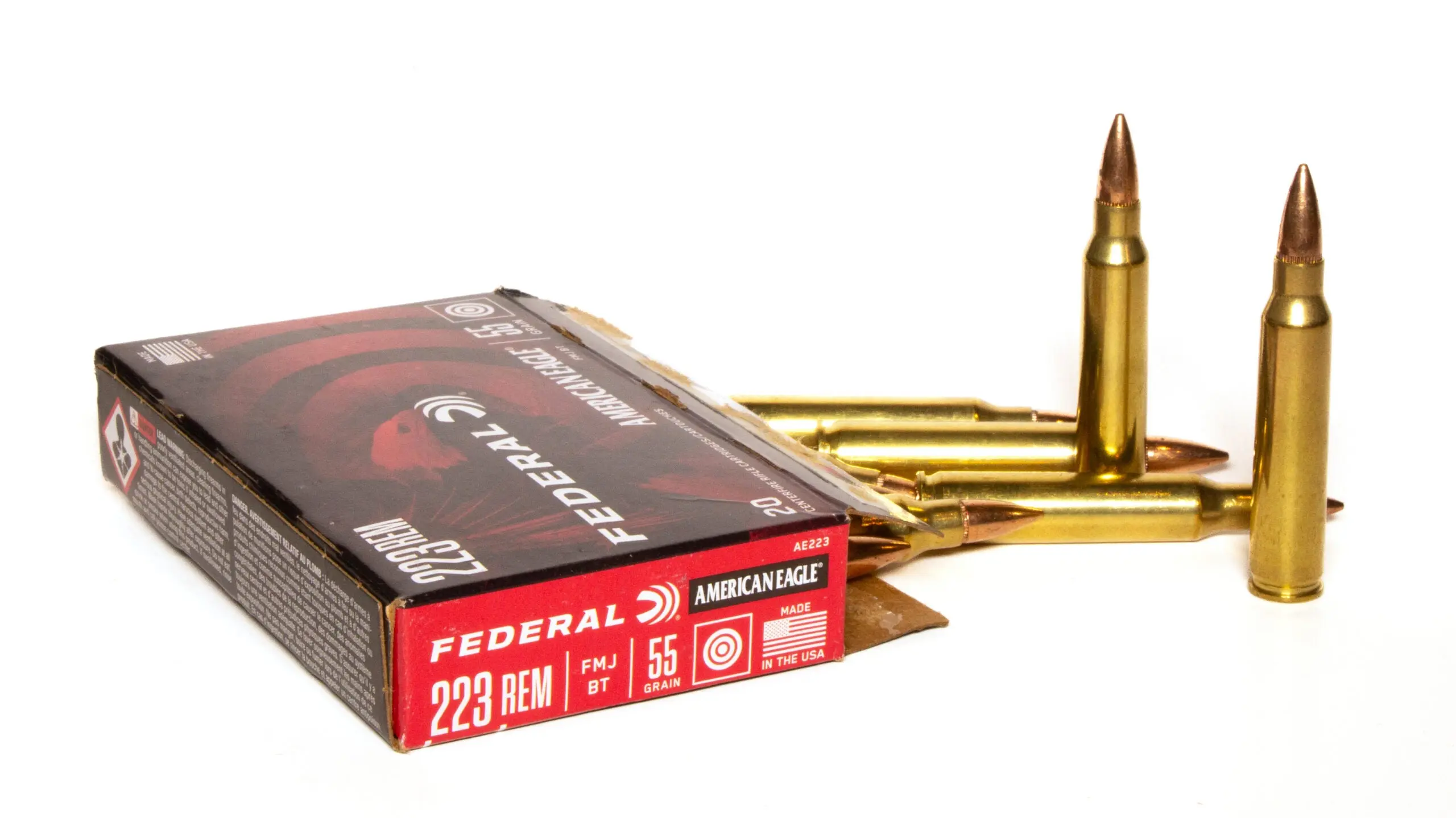 Box of 223 Remington ammo with five loose cartridges on white background