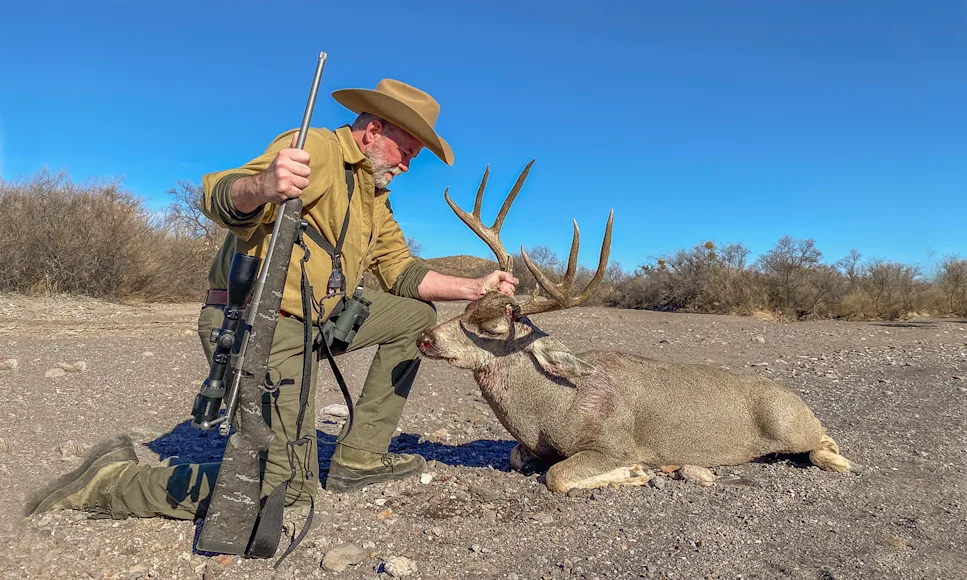 A hunter poses with a whitetail buck.
