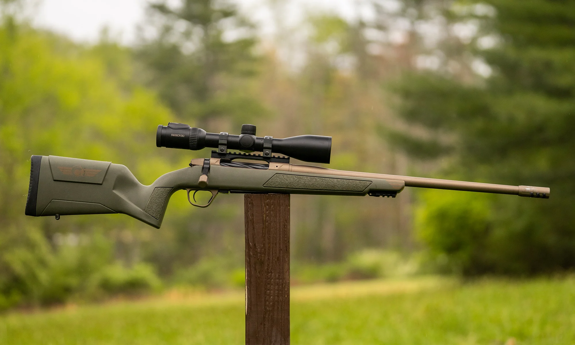 Christensen Arms Evoke bolt-action rifle balanced on a post with woods in background. 