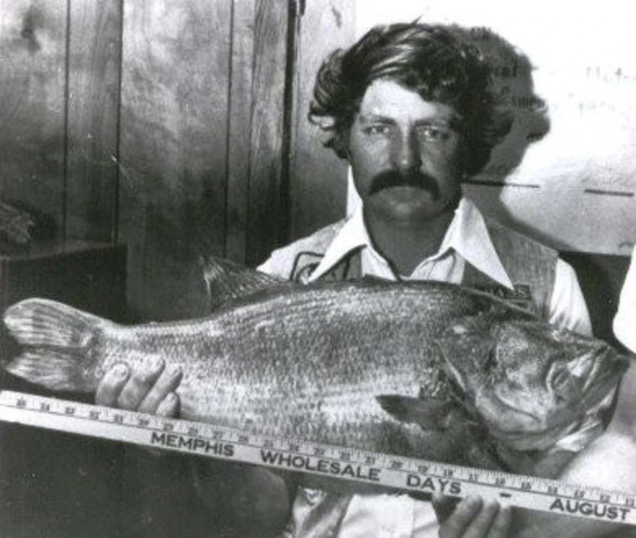 An angler poses with the Arkansas state record for largemouth bass. 