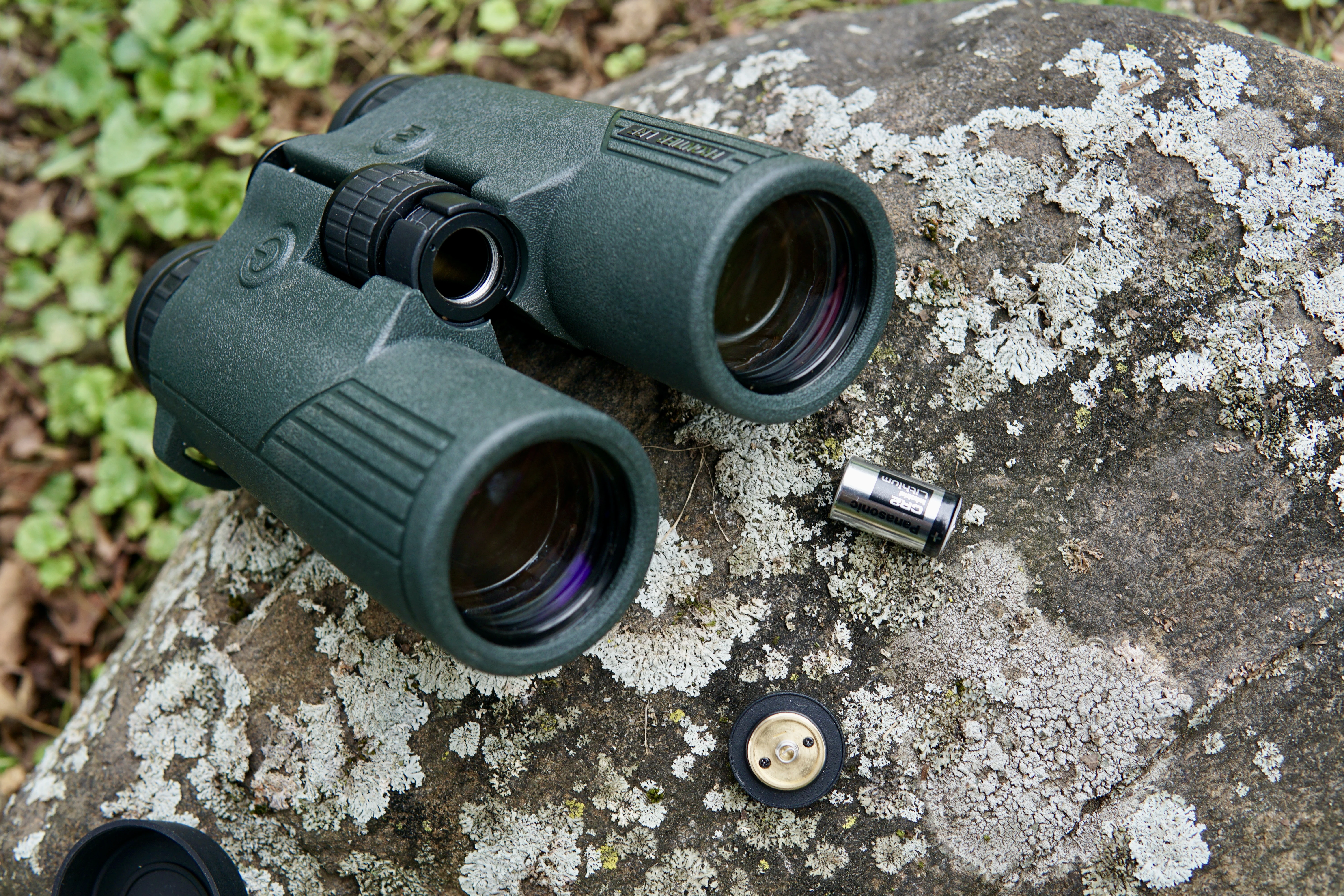 The Hawke Frontier LRF binocular sitting on a rock with the battery out. 