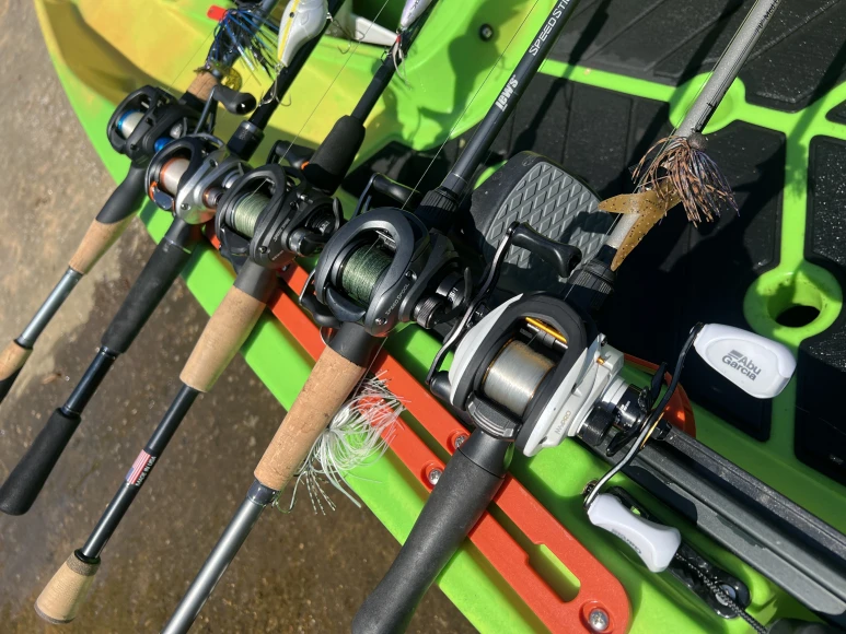 Five fishing rods lined up across the deck of a kayak.