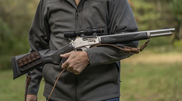 A shooter holds a Marlin 1895 lever-action rifle with leather carry strap in the crook of his arm.