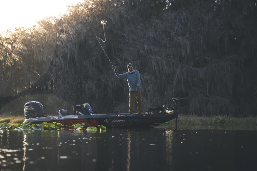 Angler casting a lure from the bow of a bass boat