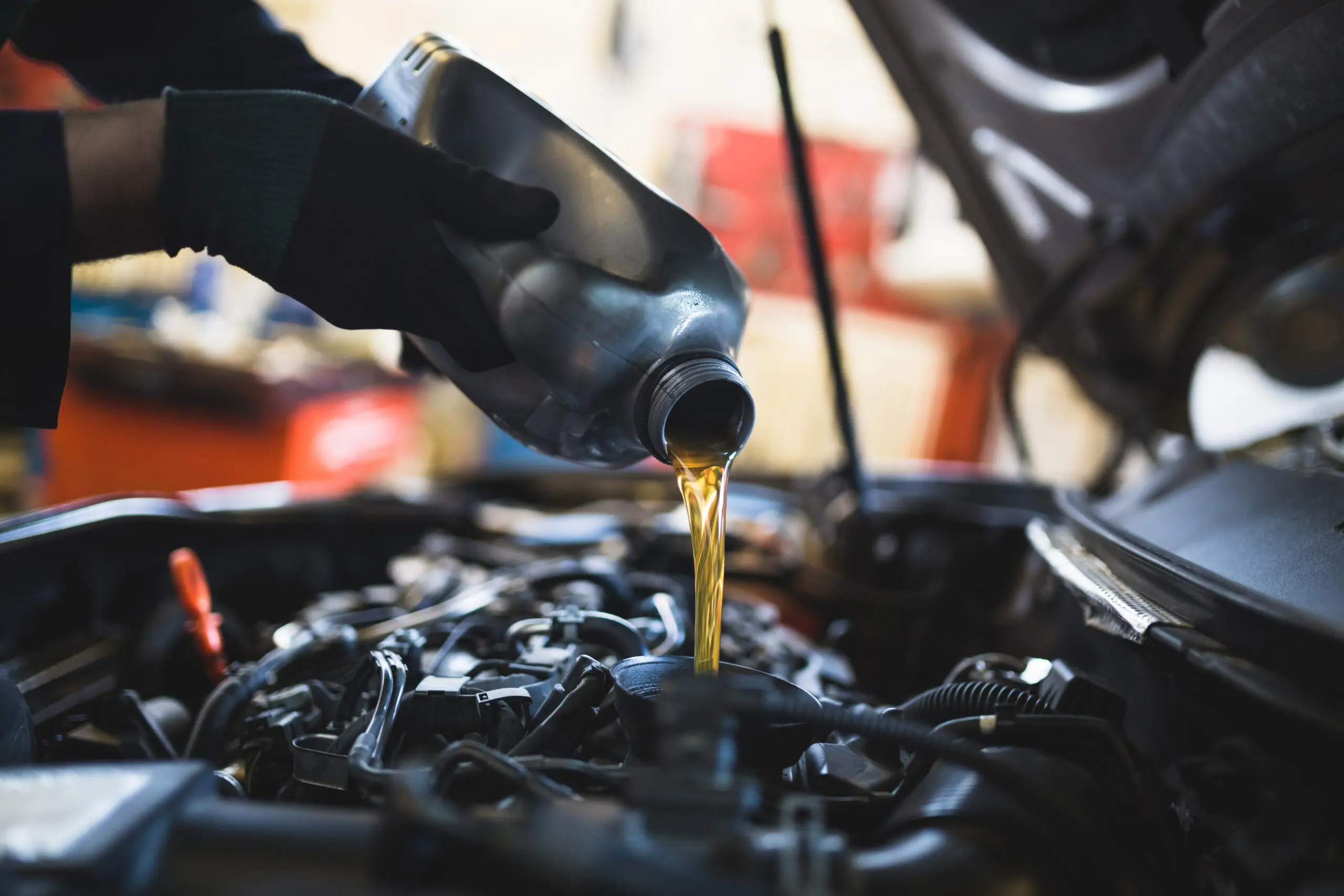 Gloved hands pouring oil into a engine