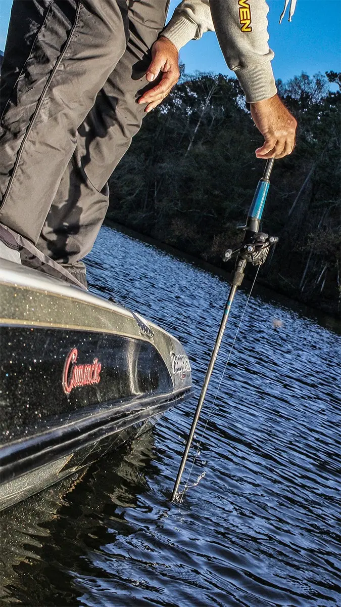 An angler in a boat dips his rod tip into the water to release a snagged lure