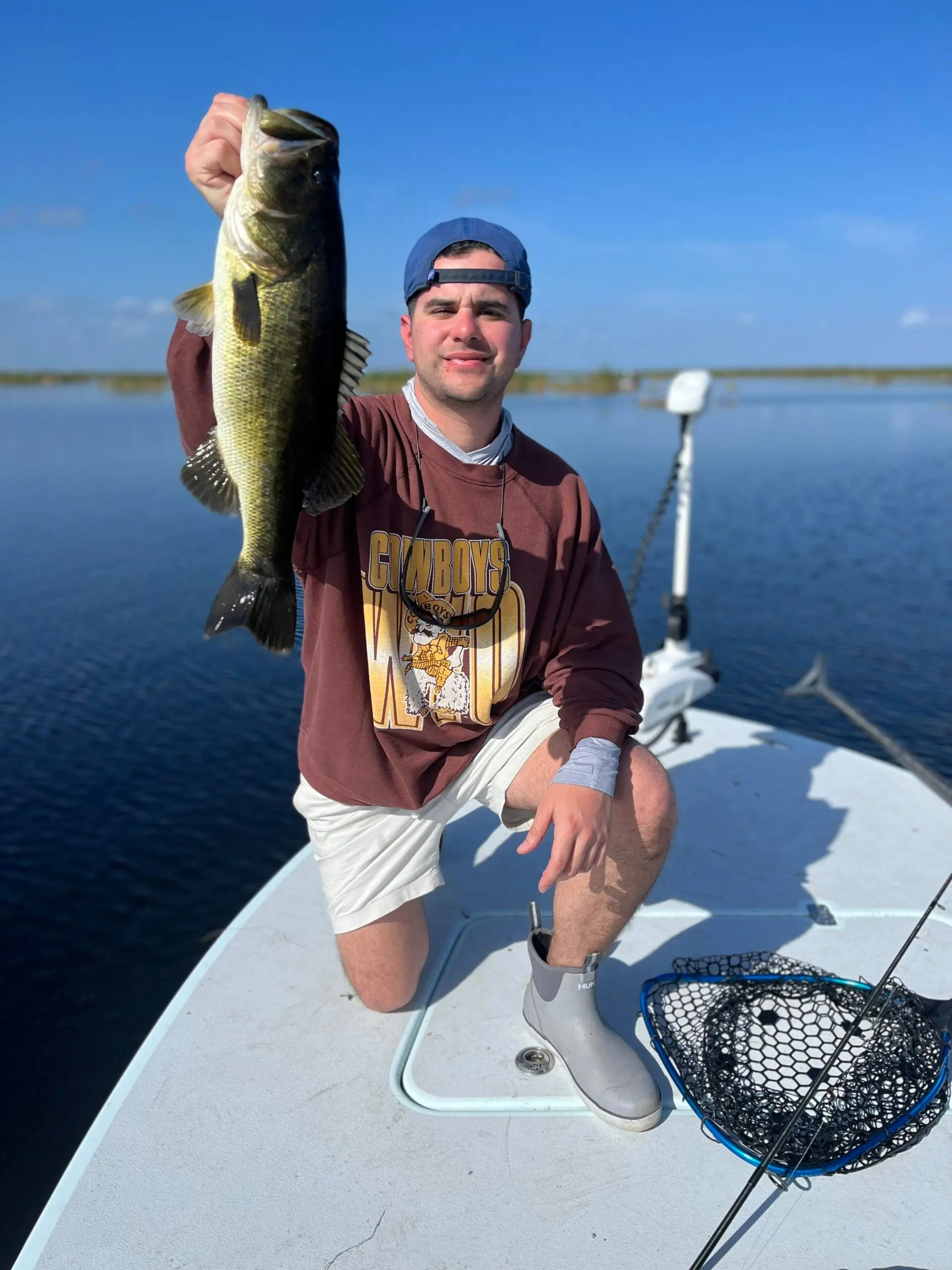 Angler holding largemouth bass caught in Florida on boat