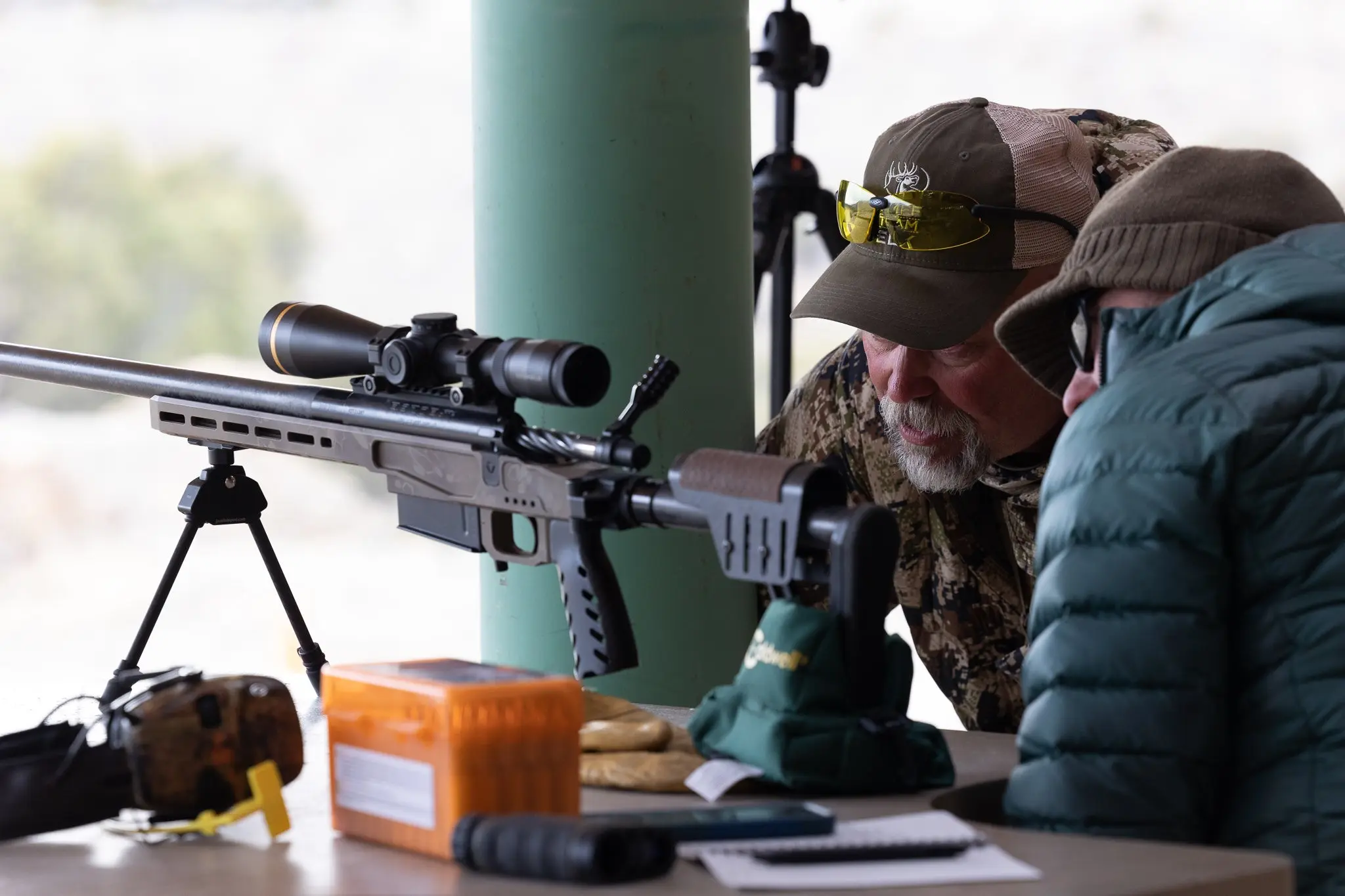 Two men looking at a long-range rifle.