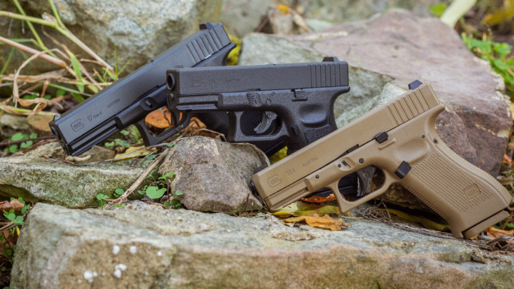 Three Glock air pistols sitting on rocks